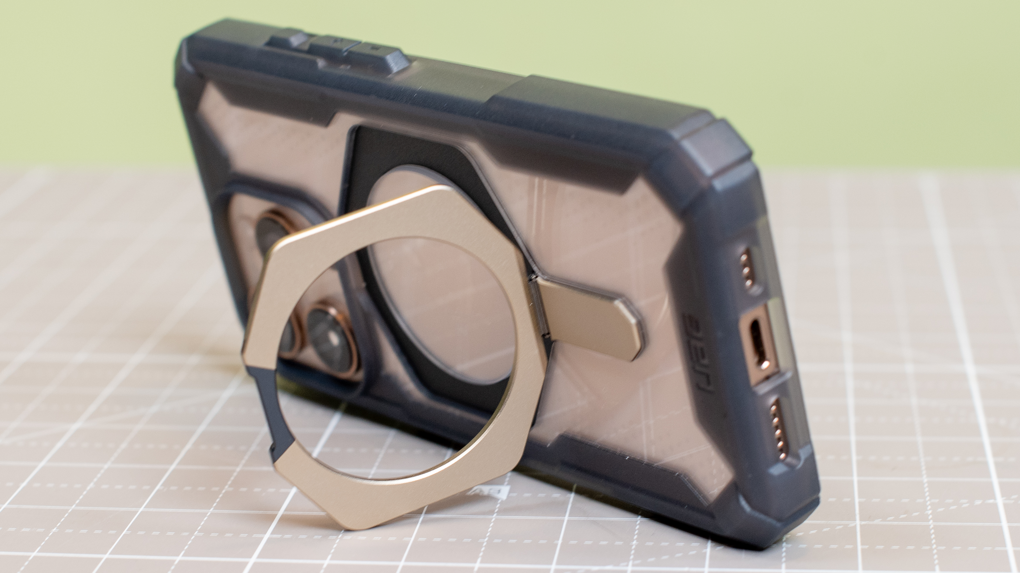 Urban Armor Gear Plasma XTE from back showing kickstand holding up iPhone 16 Pro desert titanium