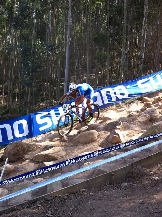 A rider sits far back on his bike to cope with the steep, downhill rocky section