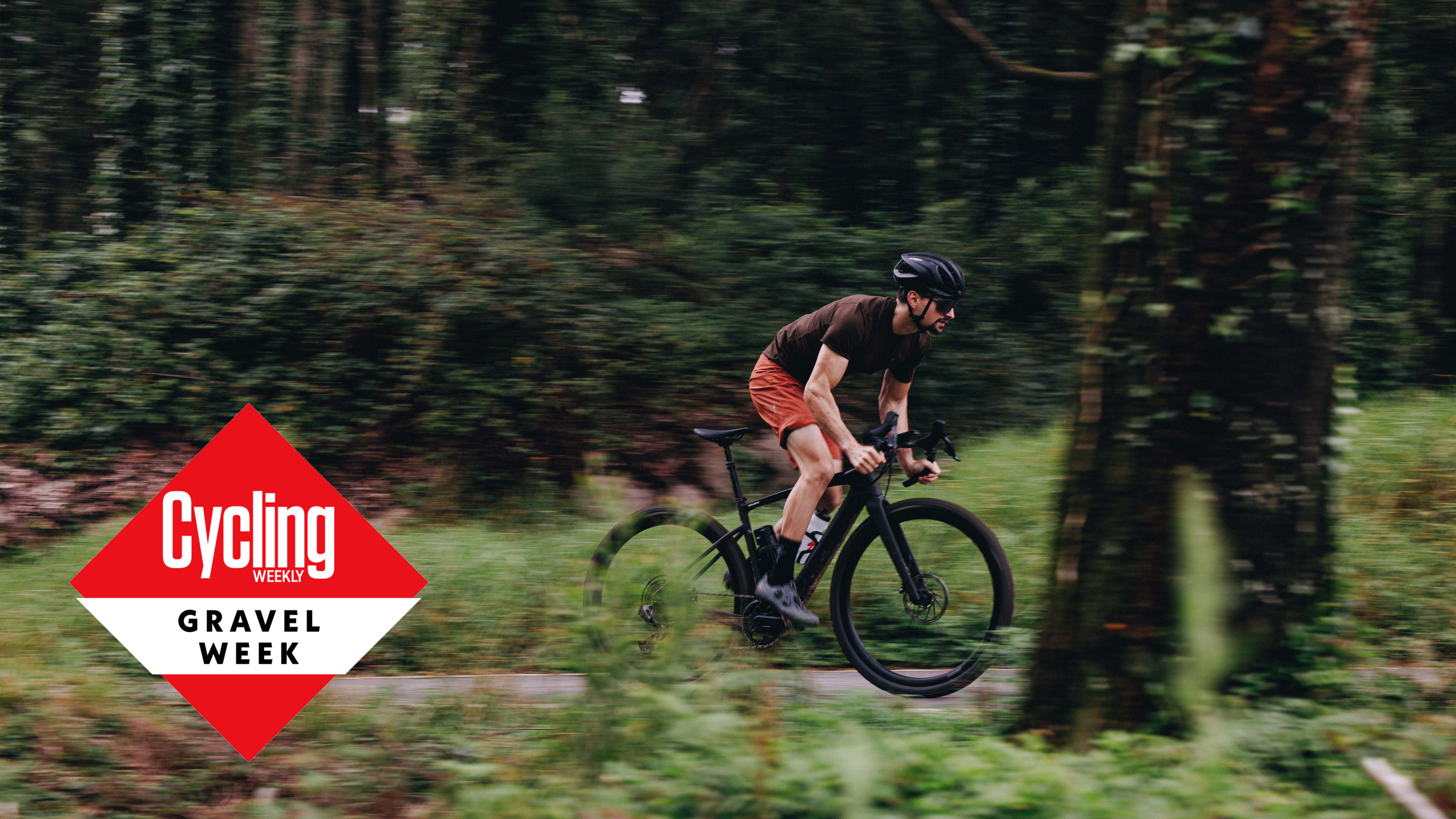 A rider out the saddle, pedalling hard and racing through the forest on one of the best electric gravel bikes. 