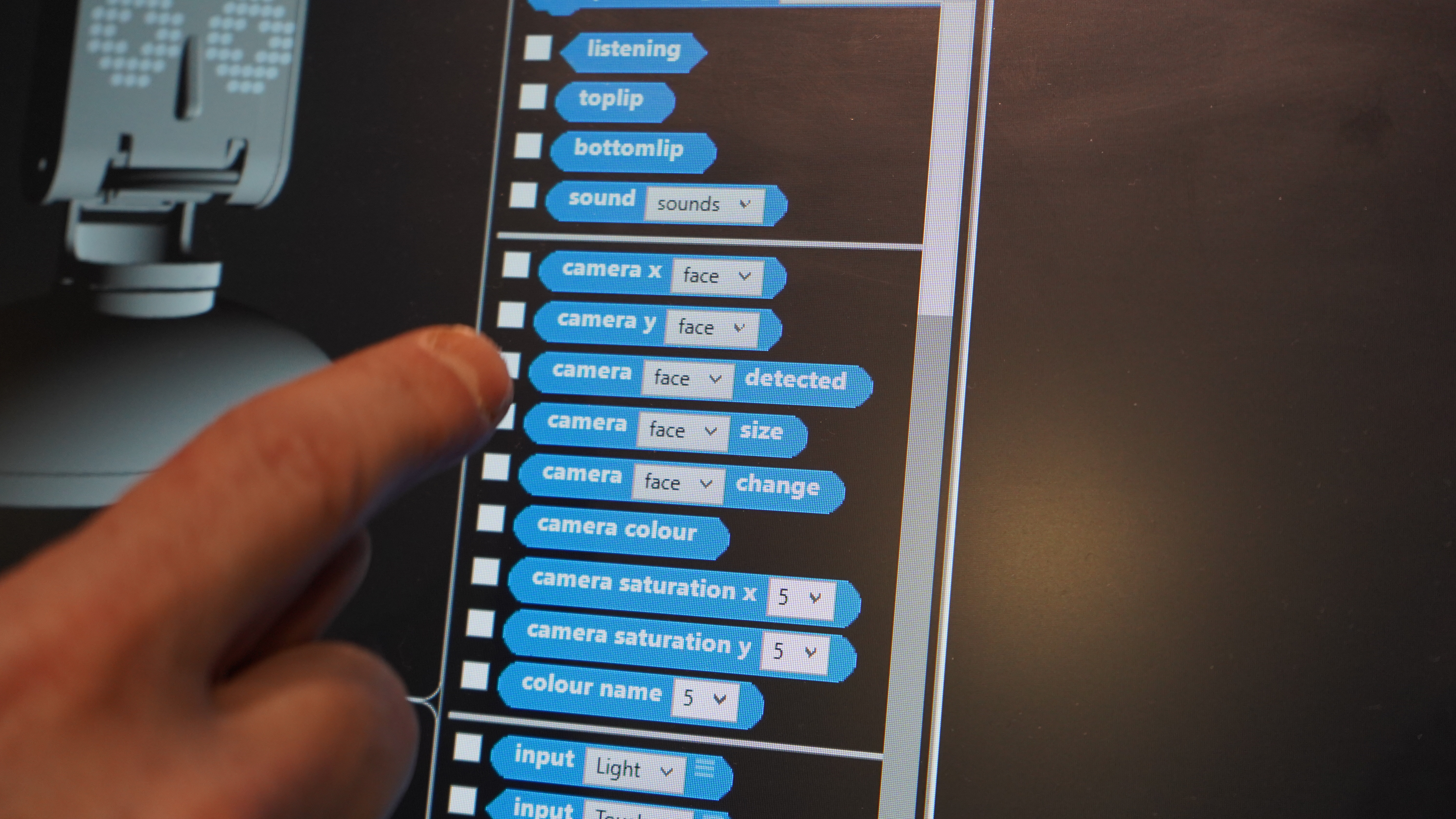 Screen of Ohbot programming computer with finger