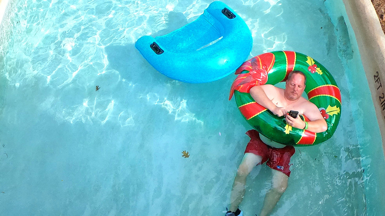 Man captured using his cell phone in the Blizzard Beach lazy river pool at Walt Disney World resort.