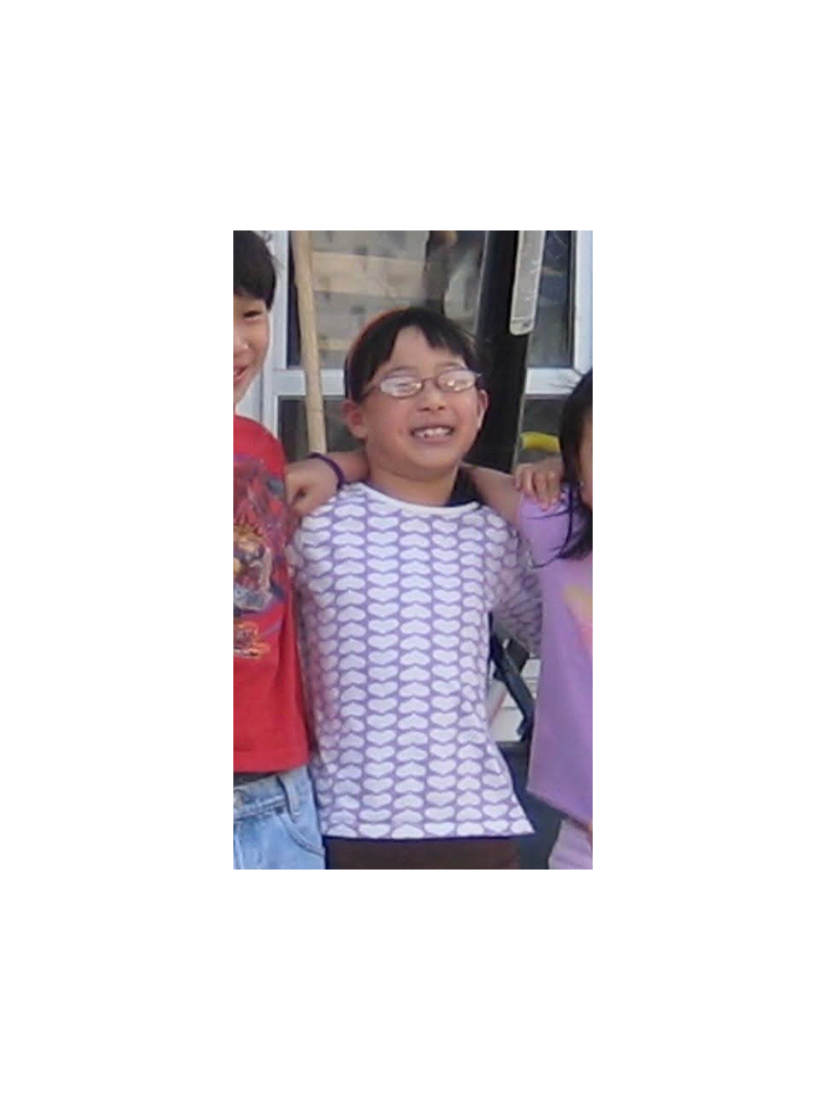 Kristina Ang when she was young wearing her glasses with a purple printed T-shirt.