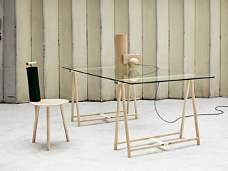 Clear glass table with wooden legs with a mathching wooden chair, photographed on grey flooring