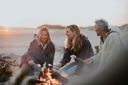 a group of adults roasting marshmellows around a campfire