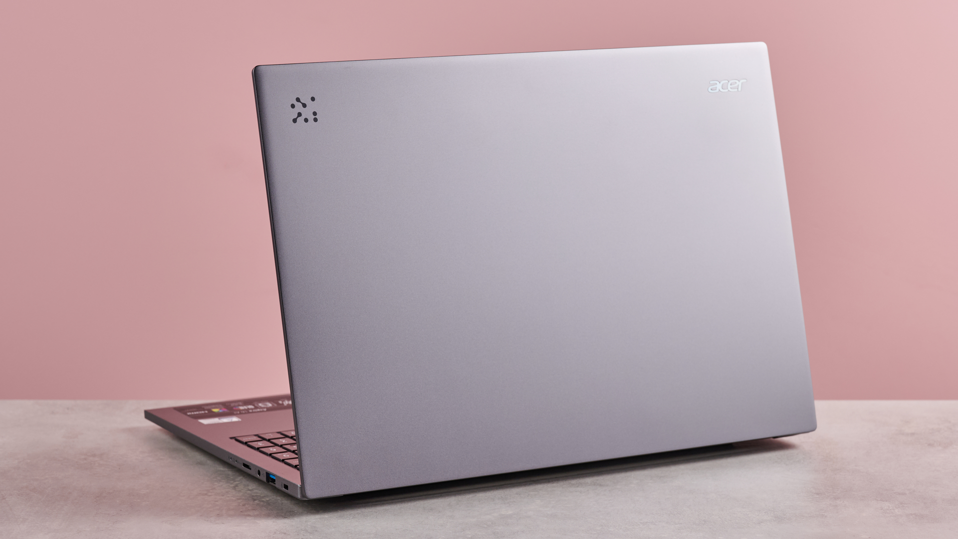 Back of Acer Aspire 16 AI open on table with pink background
