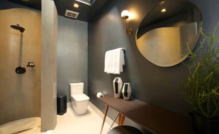 Bathroom with concrete-like walls, brass and whitewashed oak flooring