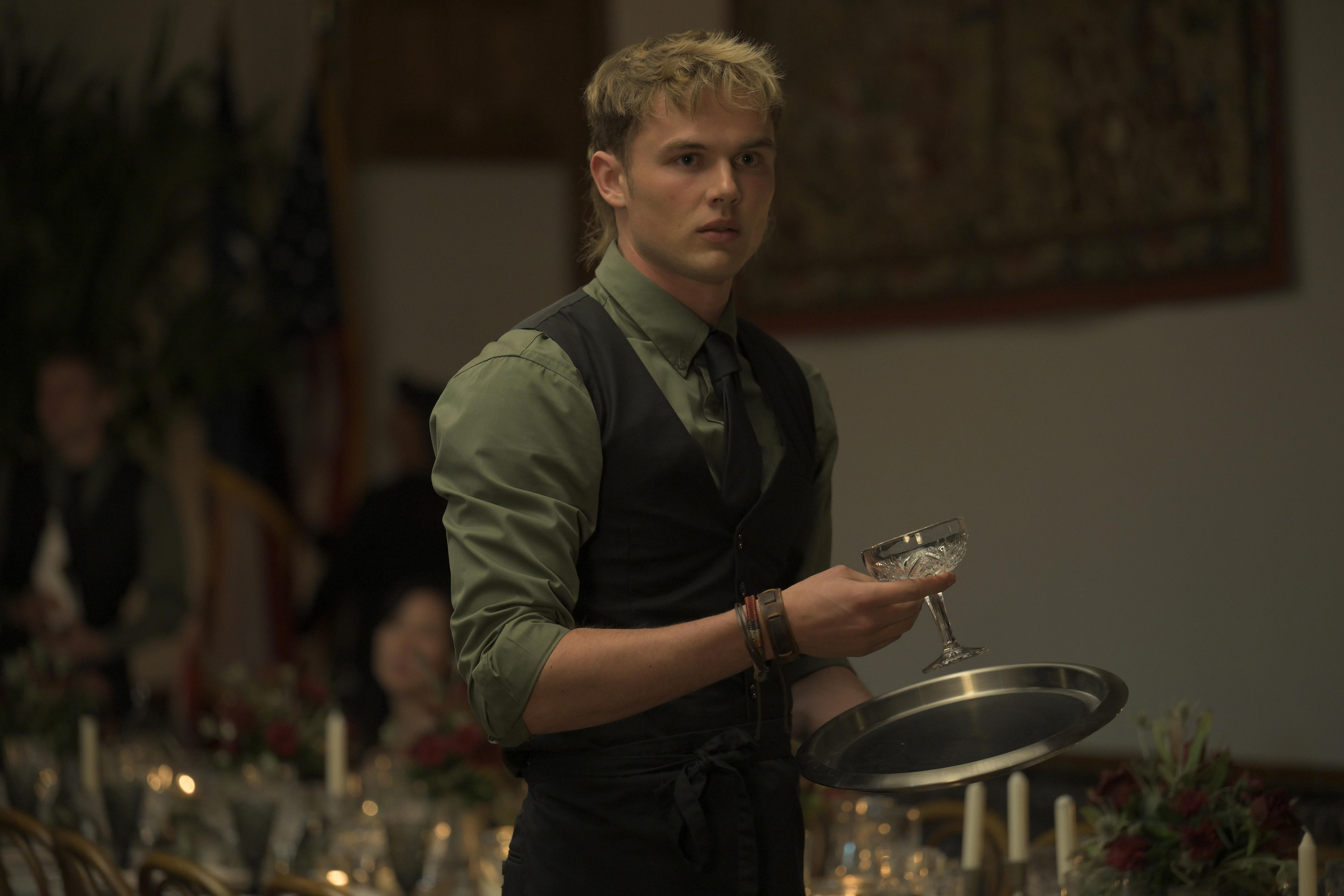 Garrett Wareing as Lucas, holding a glass and serving platter in Episode 102 of Netflix's 'Ransom Canyon.'