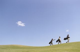 Golfers carrying bags