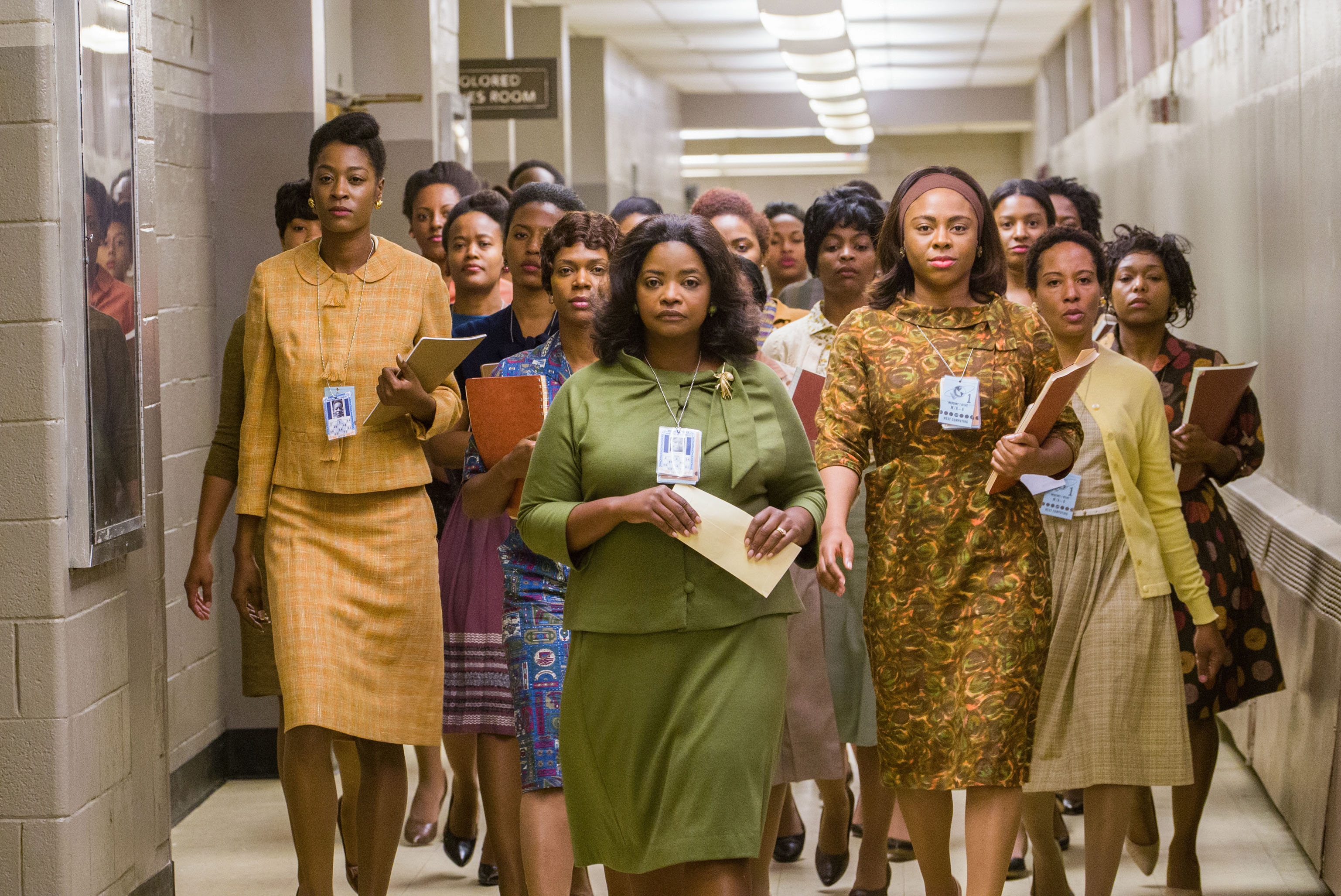 A large group of women walks down a hallway