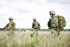 Three soldiers stand in a field.