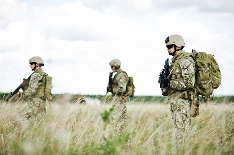 Three soldiers stand in a field.