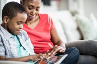 mother and son using tablet for home-schooling as schools close