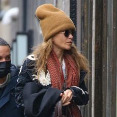The Olsen twin wearing a similar-sized tan beanie, black coat, black pants, and red scarf in New York City on January 1, 2023.