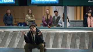 Owen sits on the baggage carousel in the airport in The Recruit season 2