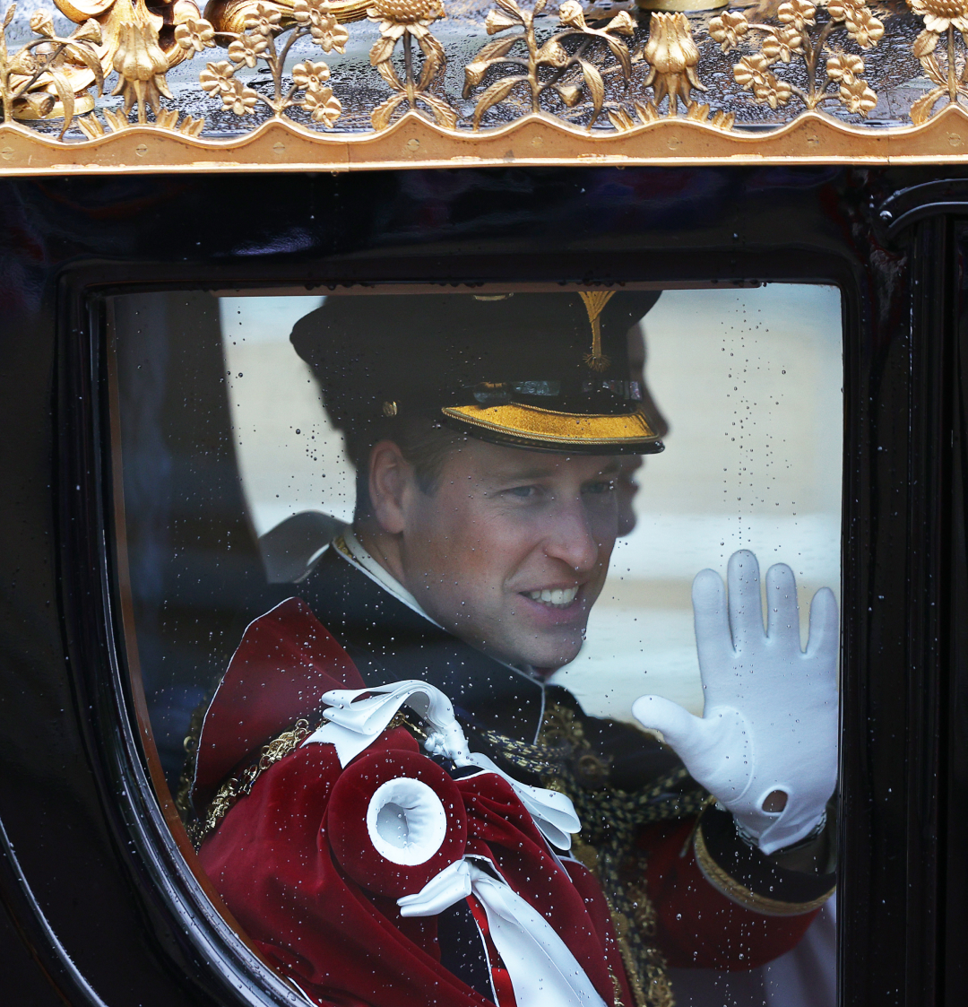 Prince William waving from a gold carriage at King Charles's coronation