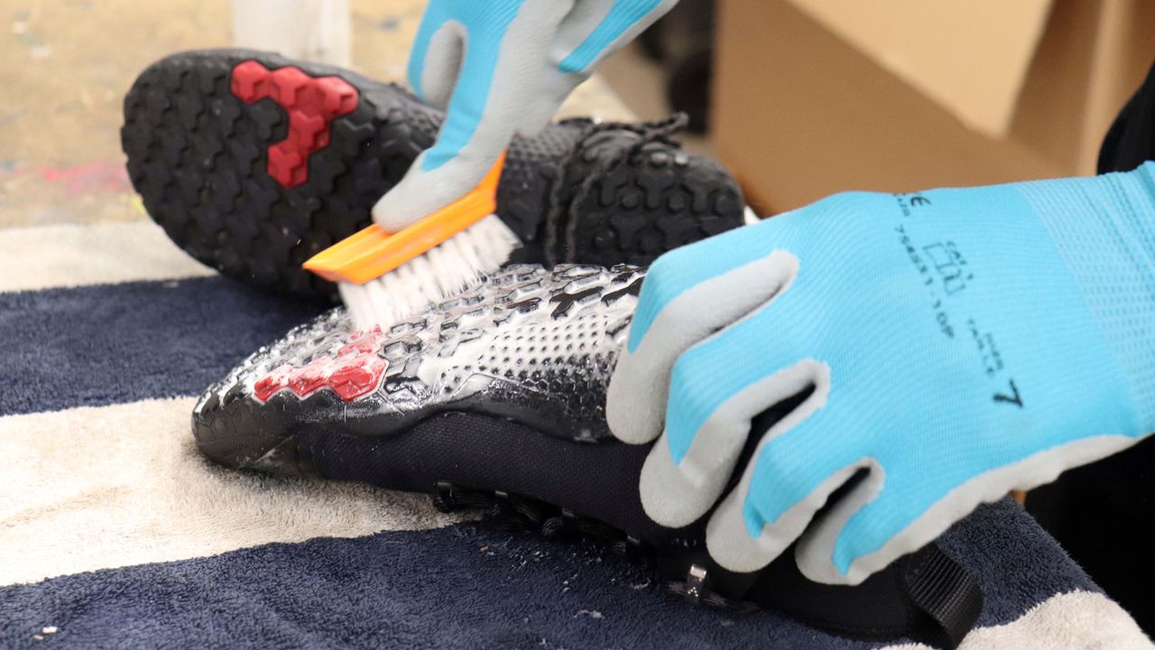 Person scrubbing a shoe using soapy water