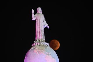 The fully eclipsed Beaver Moon passes behind the Divine Savior of the World Monument in San Salvador, El Salvador on Nov. 8, 2022. (Photo by Kellys Portillo/APHOTOGRAFIA/Getty Images)