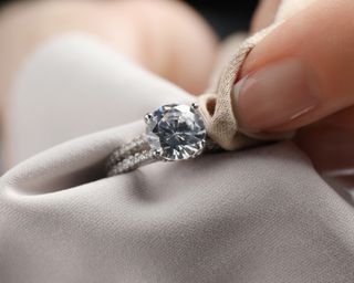 Person cleaning diamond ring with microfiber cloth