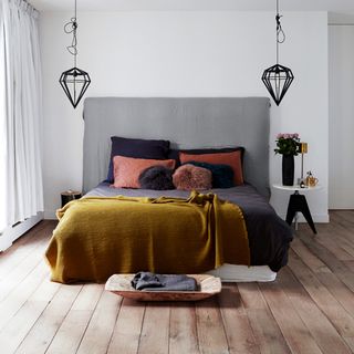 bedroom with white walls wooden flooring and bed with cushions