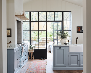 A pale blue kitchen with rug and doors to backyard