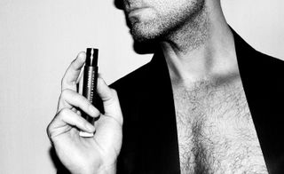 Black and white image of man holding perfume oil roll-on