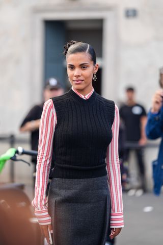 woman wearing a striped shirt, a cropped sweater vest, and a pencil skirt