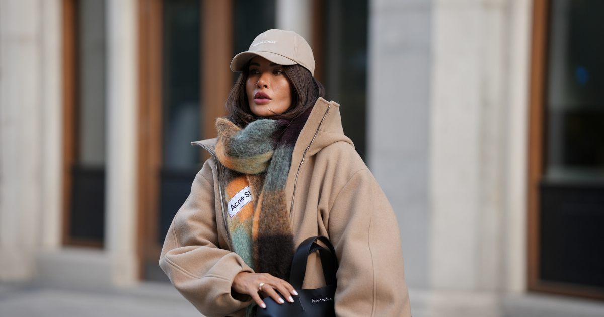 cold weather skincare Füsun Lindner is seen wearing a beige baseball cap with minimal branding from Canada Goose; an oversized checked scarf in muted earthy tones, with a soft and fluffy texture from Acne; 