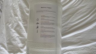 OTTY Memory Foam Mattress Topper in its packaging on the bed