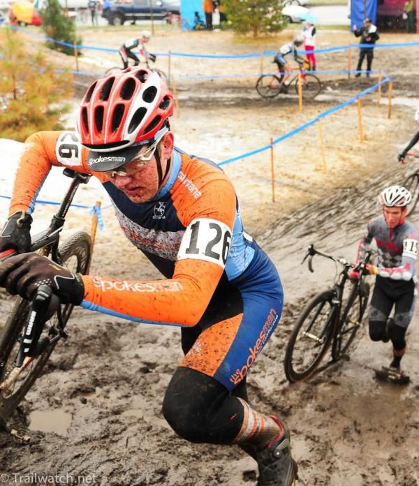 Zach Colton pushing his bike on the muddy run-up