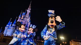 Mickey Minnie and Goofy in front of Cinderella Castle at night dressed for Starlight: Dream the Night Away parade