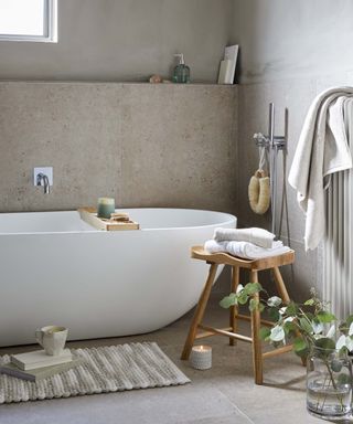 Rustic bathroom ideas: white freestanding bath with wooden stool and bathroom accessories by Dunelm