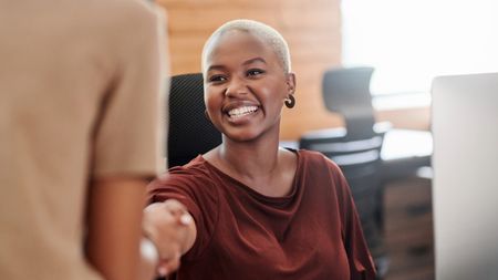 Young, happy businesswoman shaking hands in an office 