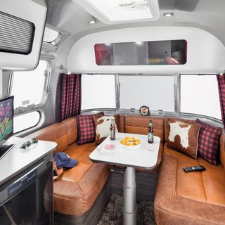 airstream model with brown leather seat and cushions with drinks on table