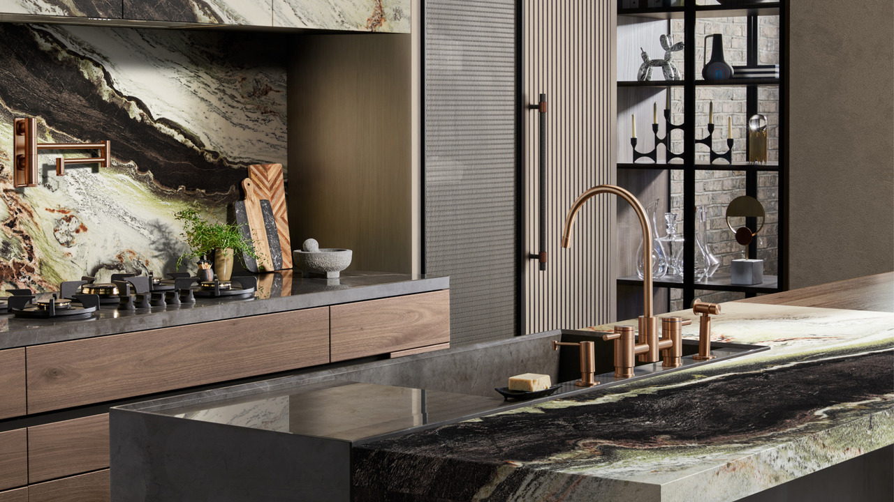 Sleek modern marble kitchen with wooden cabinetry and copper finishes. The kitchen island has a sink within with copper taps