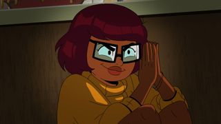 Close up of Velma (Mindy Kaling) rubbing her hands together and smirking
