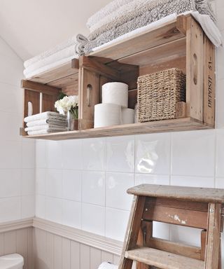 White bathroom with wooden fruit boxes used as shelves
