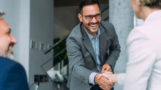 A financial adviser, insurance agent or business colleagues handshaking across the table during a meeting in modern office. 