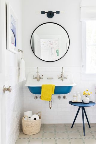 A bathroomi idea with white wall decor, a blue basin and small black side table