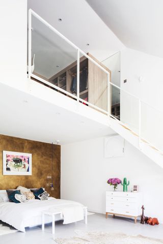 white bedroom with a feature gold metallic wall, and a mezzanine