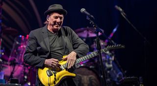 Adrian Belew wears all black and works some slide magic on his gold Parker Fly, onstage with the Beat tour