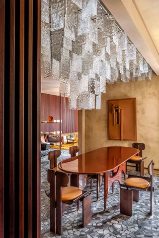 A spectacular, transparent Murano glass chandelier hangs over a wood-drenched living room.