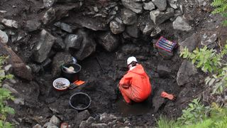 an archaeologist digs at the bottom of a well