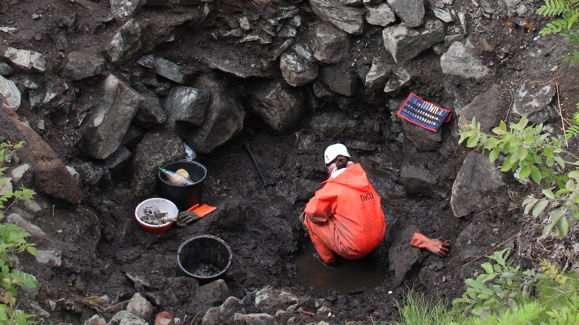 an archaeologist digs at the bottom of a well