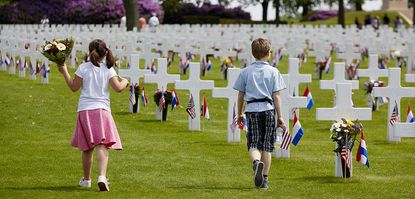 Children bring flowers to the Netherlands American Cemetery.