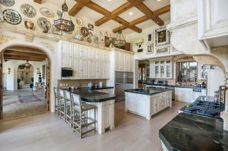 The white kitchen of Sugar Ray Leonard's house, with plates on the wall and beamed ceiling