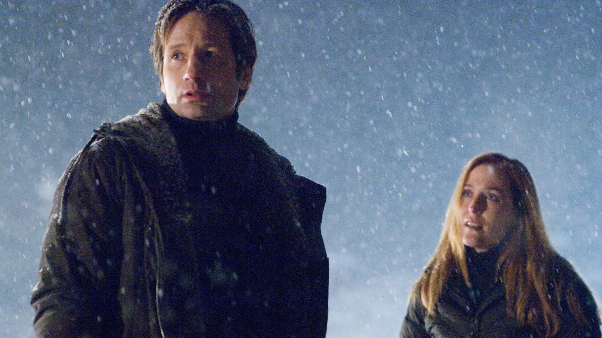 A still from the movie X Files I want to believe starring Gillian Anderson as Dana Scully and David Duchovny as Fox Mudler standing in a snowstorm