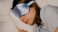 A woman sleeping on her side wearing a blue sleep mask