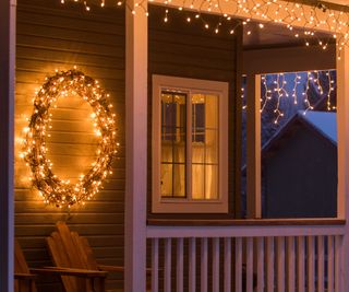 A lit Christmas wreath on a veranda