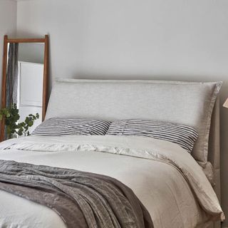 Grey bed frame with cushion on headboard