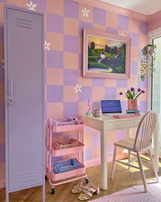 A purple and pink study area with a wooden desk and chair, plus a storage trolley